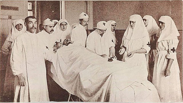 В операционной (в центре, склонившись над раненым — княжна В.И. Гедройц, справа от нее — Александра Федоровна с дочерьми Татьяной и Ольгой Николаевной)